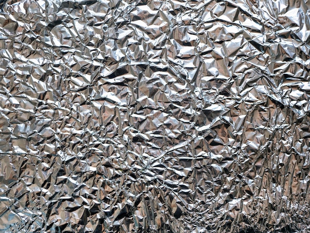 Zdjęcie tekstura fotograficzna losowo zmiętego arkusza folii aluminiowej