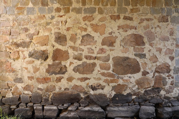 Tekstura kamiennej ściany z wieloma dużymi brązowymi i szarymi kamieniami uzbrojonymi w cement Stary zamek kamienny mur tekstury tła do użytku średniowiecznego Część kamiennego budynku