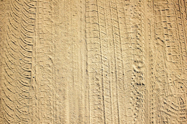 Tekstura piaszczystej drogi Piasek drogowy Żółty piasek w słońcu z samochodem i śladami Piaskowa droga nasypu