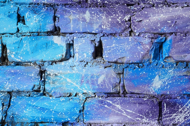 Tekstura starego ceglanego muru pomalowanego na niebiesko i fioletowo z niedbale rozmieszczonymi białymi kroplami i plamami, które wizualizują gwiazdy w kosmosie