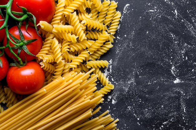 Tekstura surowego spaghetti, fusilli i świeżych pomidorów. Koncepcja żywności. Składniki do gotowania włoskiego makaronu. Skopiuj miejsce