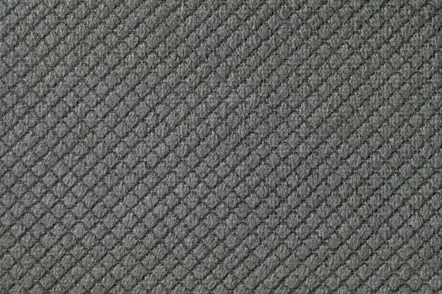 Tekstura tło ciemnoszare puszyste tkaniny z romboidalnym wzorem, makro. Abstrakcyjne tło z dekoracyjnego czarnego tkanego materiału tekstylnego.