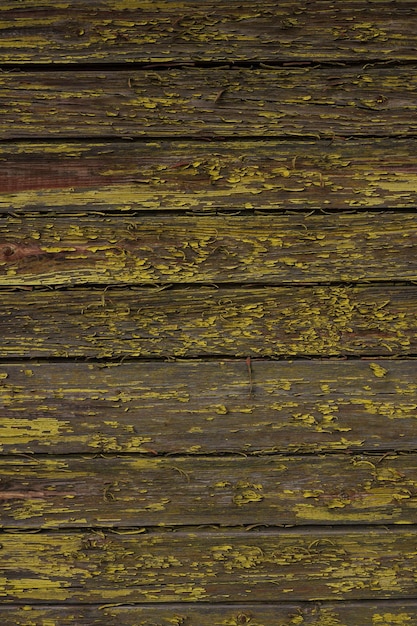 Teksturowane tło postarzanej ściany z drewnianymi deskami z żółtą łuszczącą się farbą