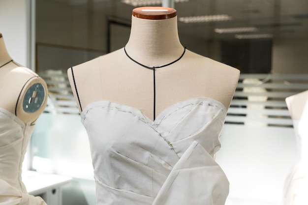 Tekstylny manekin krawiecki z czarnymi liniami pokrytymi płóciennym wzorem i drapowaniem dla krawców pracujących i projektujących nowe kolekcje mody w warsztacie krawieckim atelier