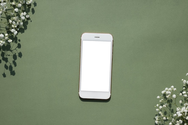 Telefon komórkowy makieta na pastelowym zielonym tle ozdobionym białymi małymi kwiatami