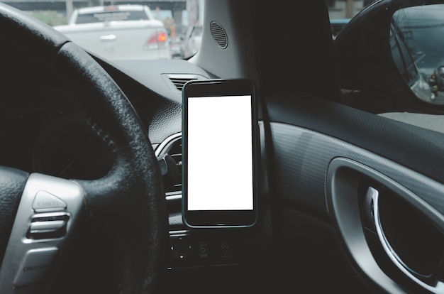 Telefon komórkowy na otwór wentylacyjny samochodu. Puste z białym ekranem. Makieta inteligentnego telefonu w samochodzie.