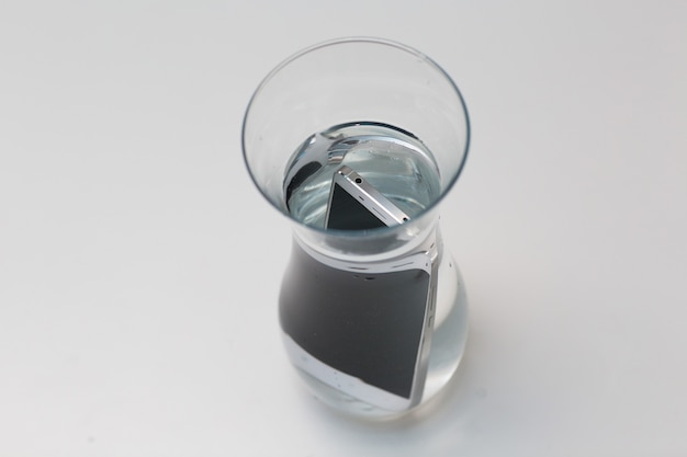 Telefon komórkowy wodoodporny w naczyniu z wodą.