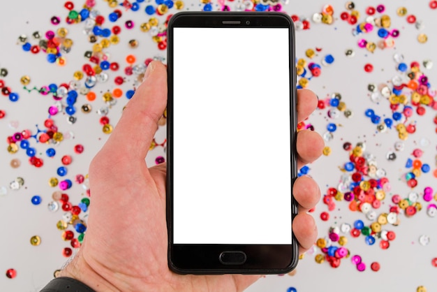 Telefon komórkowy z białym ekranem na świątecznym tle w dłoni