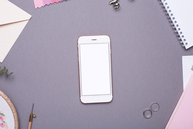 Telefon komórkowy z białym notesem, różowym notesem i szarym haftem