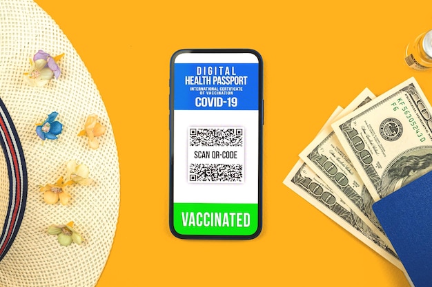 Telefon komórkowy z certyfikatem szczepienia przeciwko wirusowi koronawirusa covid19 cyfrowa aplikacja na ekranie wakacje letnie mieszkanie leżące tło widok z góry zdjęcie