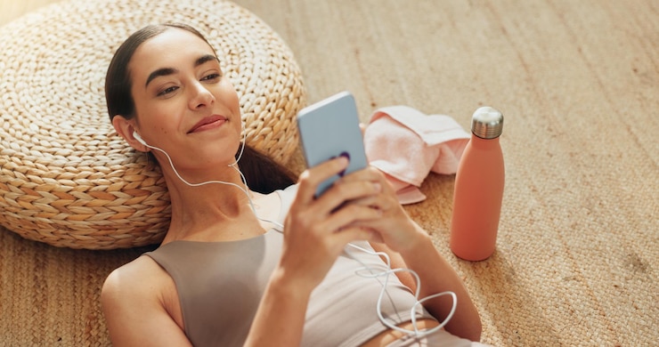 Zdjęcie telefon muzyczny i ćwiczenia z kobietą w domu dla strumieniowego podcastu fitness i pokoju zrelaksować się w internecie i aplikacji wellness z osobą słuchającą zen audio na podłodze dla zdrowia psychicznego jogi i pilates