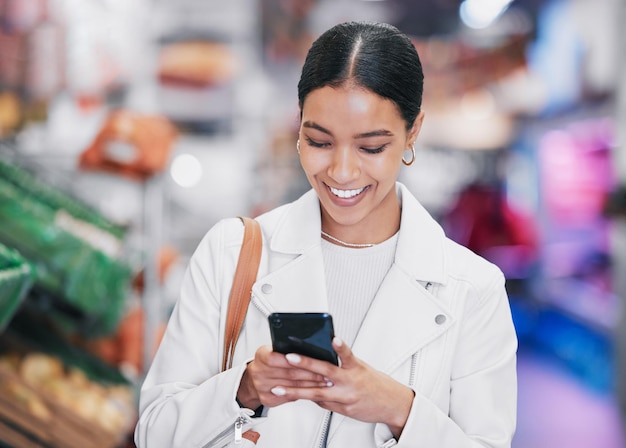 Telefon w supermarkecie lub kobieta z uśmiechem w sklepie spożywczym, która prowadzi badania e-commerce lub zakupy online na zdrowym produkcie