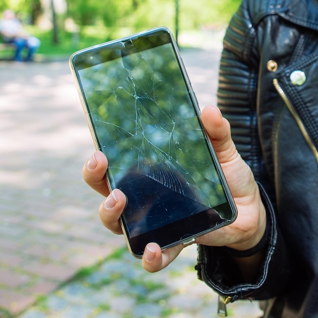 Telefon z pękniętym ekranem w dłoni sprawa nieobjęta gwarancją