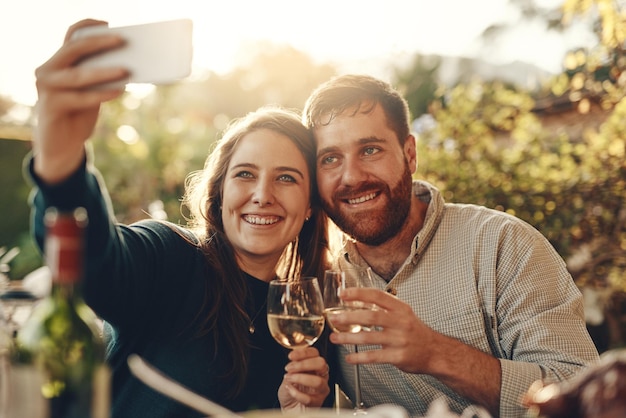 Telefon z winem i para robią sobie selfie z toastem za szczęśliwe małżeństwo i udostępniają romantyczne treści w mediach społecznościowych Kobieta uśmiecha się, robiąc zdjęcia na randce z uroczym partnerem pijącym szampana