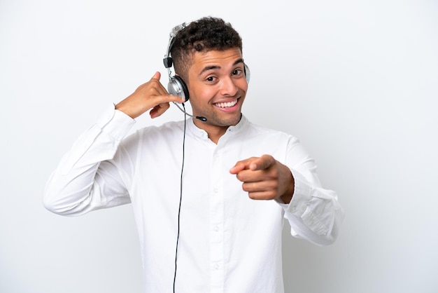 Telemarketer Brazylijczyk pracujący z zestawem słuchawkowym na białym tle wykonujący gest telefonem i wskazujący przód