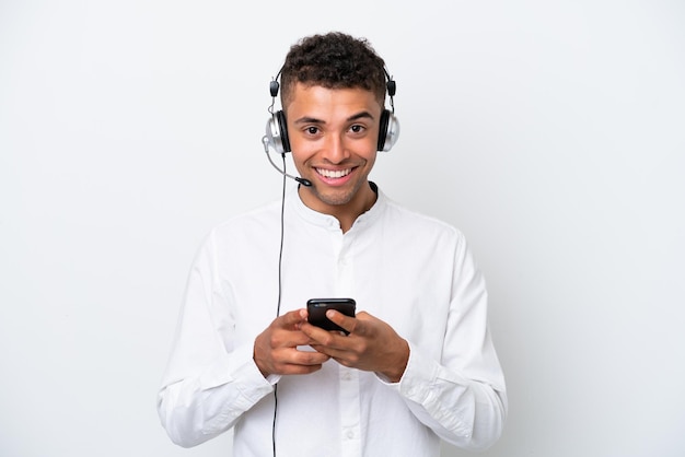 Telemarketer Brazylijczyk pracujący z zestawem słuchawkowym na białym tle wysyłający wiadomość za pomocą telefonu komórkowego