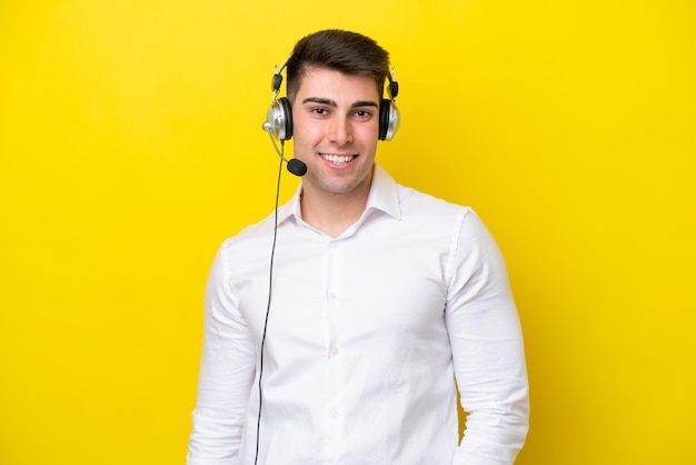 Telemarketer kaukaski mężczyzna pracujący z zestawem słuchawkowym na żółtym tle śmiejąc się