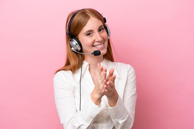 Telemarketer ruda kobieta pracująca z zestawem słuchawkowym na białym tle na różowym tle brawo po prezentacji na konferencji