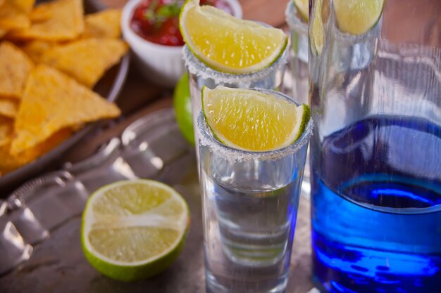 Tequila strzał z wapnem i solą morską i błękitną butelką na tacy