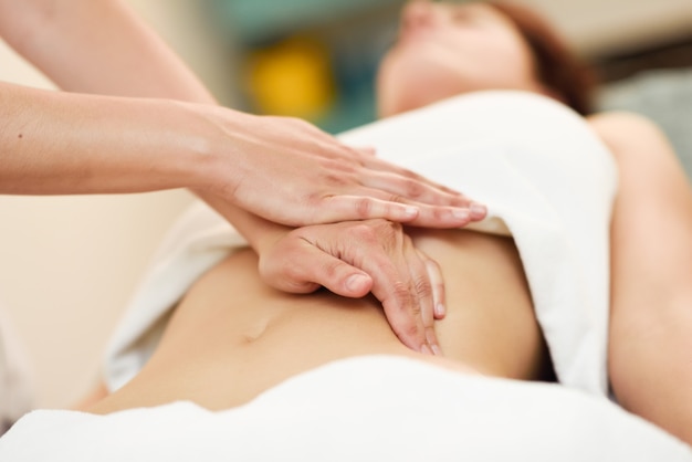 Zdjęcie terapeuta wywierania nacisku na brzuch. ręce masowania brzucha kobiety.