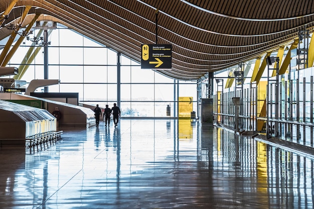 Zdjęcie terminal lotniska z ludźmi poruszającymi się sylwetkami i promieniami słońca