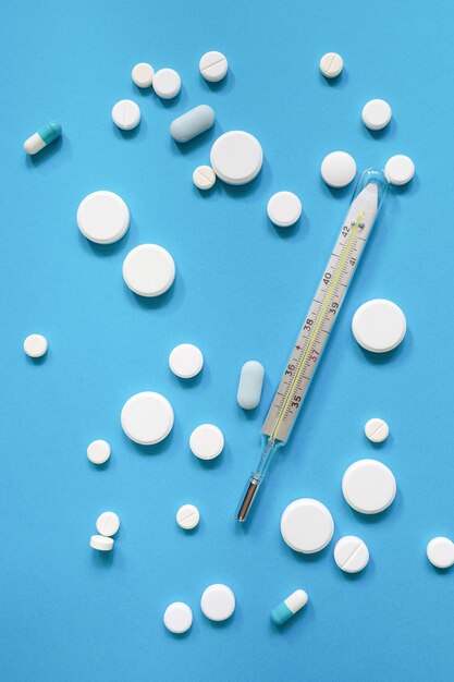 Termometr Medyczny Dużo Tabletek Przeciwgorączkowych I Antybiotyków Na Niebieskim Tle