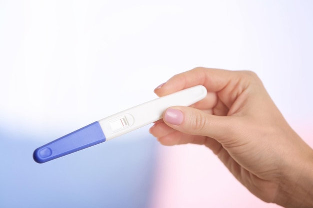 Test ciążowy w ręku na rozmytym tle salonu