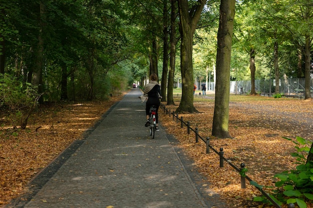 Tiergarten park Berlin Koncepcja zdrowego stylu życia Kobieta jedzie na rowerze na ścieżce Las na tle jesieni