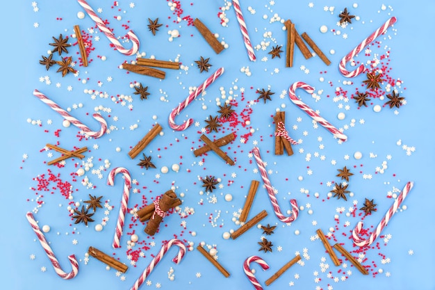 Tło bożonarodzeniowe i noworoczne ze składnikami do pieczenia trzciny cukrowej z cynamonemSłodycze posypujące świąteczne przyprawy na niebieskim tle Leżał płasko