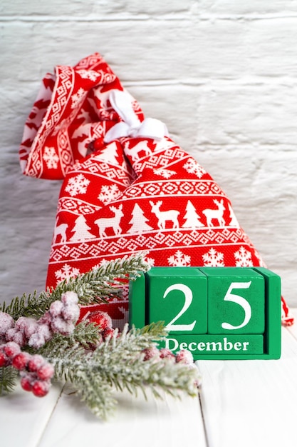 Tło bożonarodzeniowe z ozdobioną jodłą czerwoną torbą na prezent i zielonym wiecznym kalendarzem
