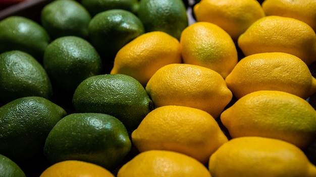 Tło Limonki I Cytryny Na Ladzie Rynku. świeża Cytryna Organiczna W Lokalnym Supermarkecie Spożywczym Rolnika. Zamknij Widok Owoców W Tekturowym Pudełku Na Półce Sklepowej.