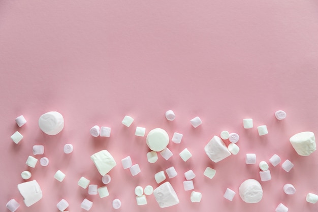 Zdjęcie tło lub tekstura różowi i biali mini marshmallows na różowym tle z bezpłatną przestrzenią dla teksta