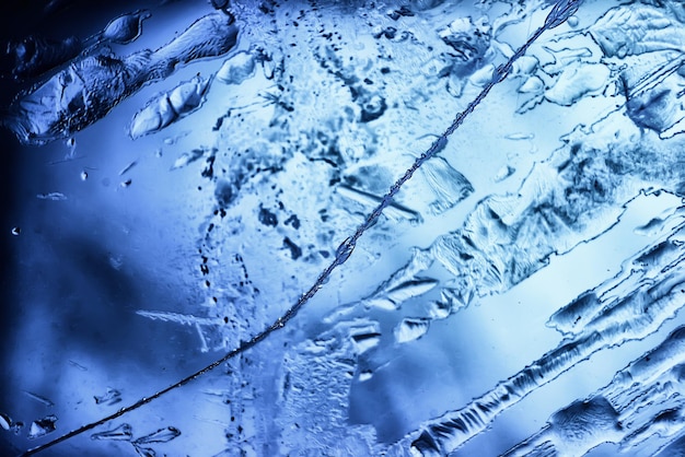 tło niebieskiego szkła lodowego, abstrakcyjna tekstura powierzchni lodu na szkle, zamarznięta woda sezonowa