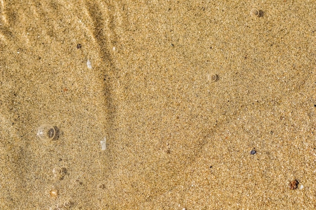 Tło piasku małe kamyki i płynące fale na plaży nad morzem Koncepcja wakacji letnich