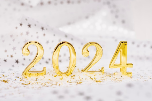 Zdjęcie tło świąt noworocznych złote liczby 2024 z drzewem noworocznym i jasnymi świecącymi światłami