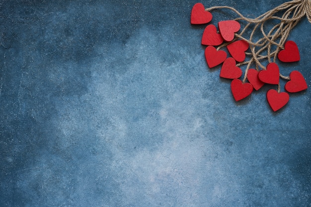 Zdjęcie tło walentynki. czerwoni drewniani serca na błękitnym tle.