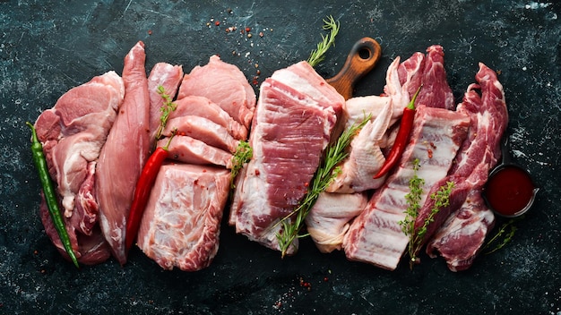 Zdjęcie tło z surowego mięsa mięso na czarnym kamiennym tle z przyprawami i ziołami widok z góry styl rustykalny