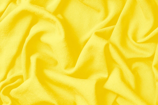 Tło z wymiętej żółtej bawełnianej tkaniny, modny kolor roku 2021.
