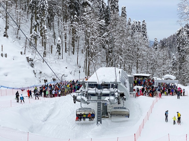 Tłum narciarzy i snowboardzistów stoi w długim tłumie do wyciągu narciarskiego