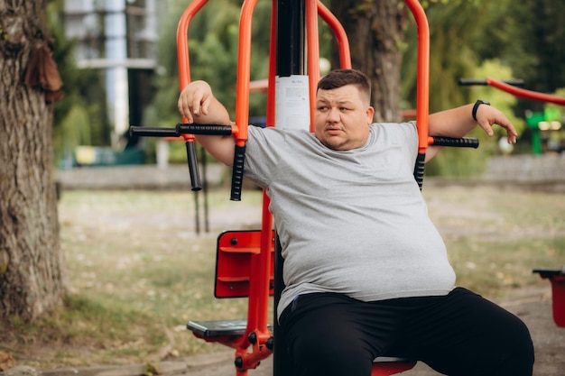 Tłusty człowiek uprawia sport w parku.