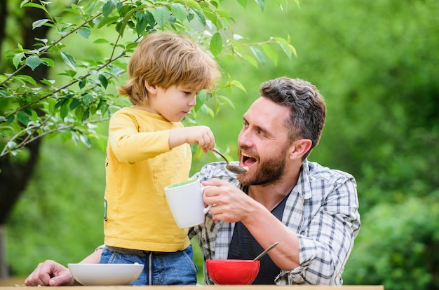 To jest dla Ciebie zdrowa żywność i dieta Dzień dziecka Szczęśliwy dzień ojca Mały chłopiec z tatą jedzą płatki zbożowe Rodzinna kolacja ojciec i syn jedzą piknik na świeżym powietrzu Poranne śniadanie