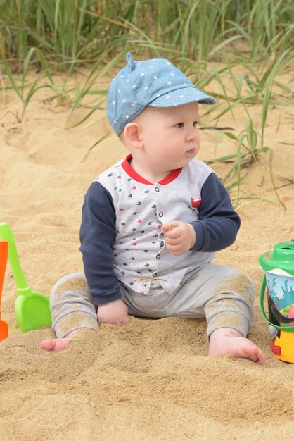 Toddler chłopiec siedzi na piasku