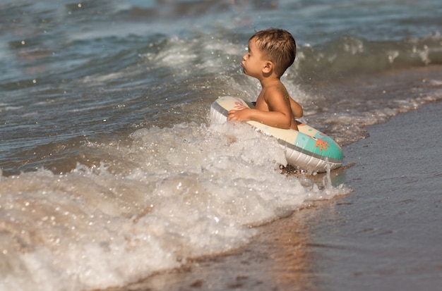 Toddler Europejski chłopiec siedzi na morzu