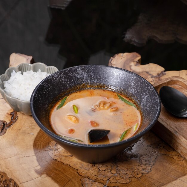 Zdjęcie tom yum zupa z owocami morza i ryżem na drewnianym stole kątowy widok