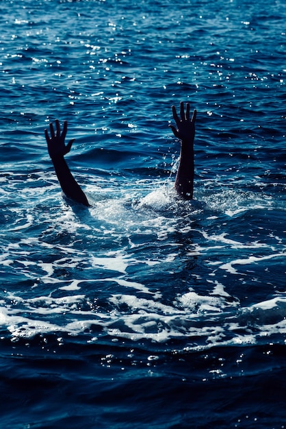 Tonący mężczyzna w morzu prosi o pomoc z podniesionymi rękami