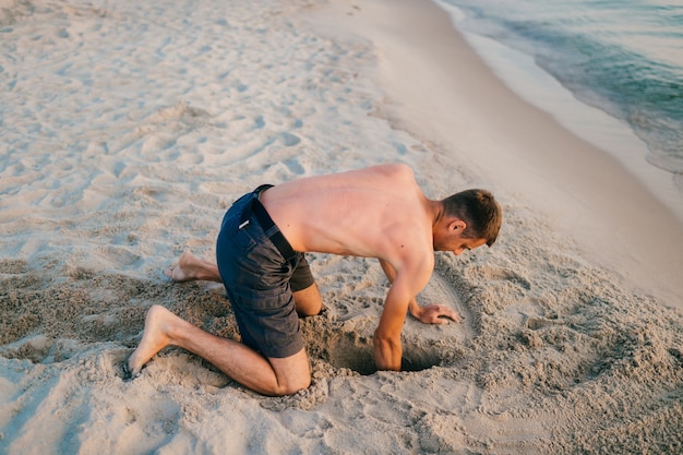 Zdjęcie topless mężczyzna na plaży kopanie dołu