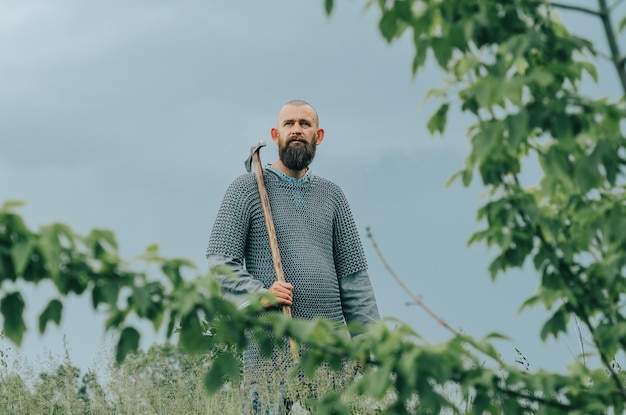 Topór w rękach średniowiecznego wojownika Wikingów Metalowy hełm i kolczuga Kręcenie filmu historycznego