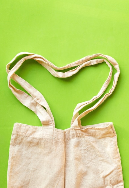Zdjęcie torba w kształcie serca uchwyty płótno tkanina tkanina eco zakupy worek makieta pusty szablon na zielonym tle. chroń koncepcję ziemi
