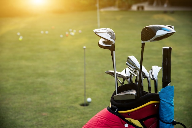 Torby golfowe i kije golfowe umieszczone na zielonym trawniku.
