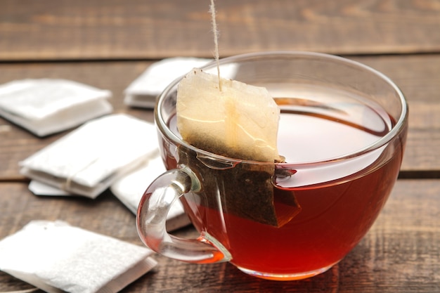 Torebka herbaty w szklanej filiżance na brązowym drewnianym tle. zrobić herbatę